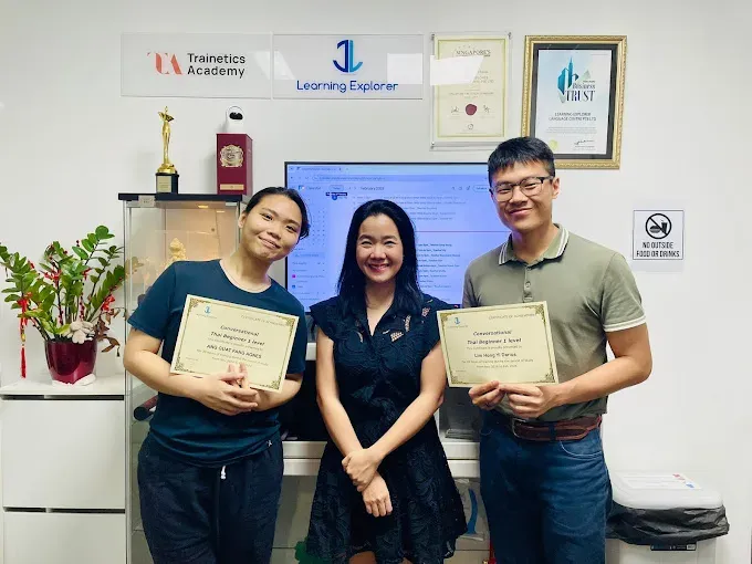 Two students and their teacher with their certificates