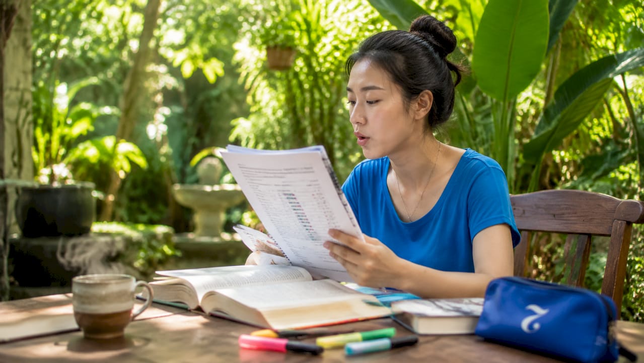Woman practicing Thai tones with guidebook