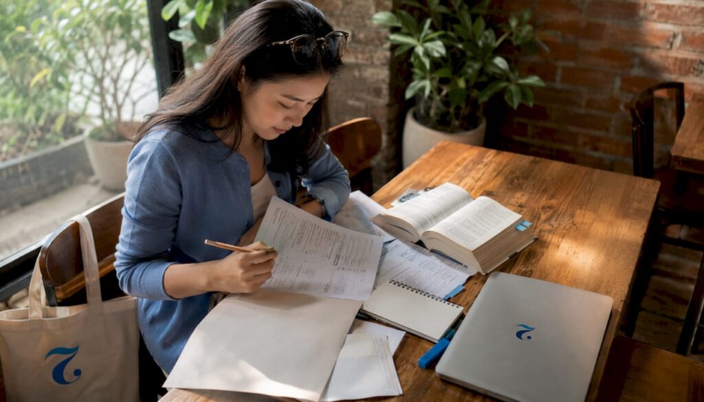Woman studying CU-TFL exam materials at home desk