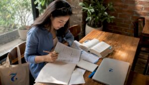 Woman studying CU-TFL exam materials at home desk
