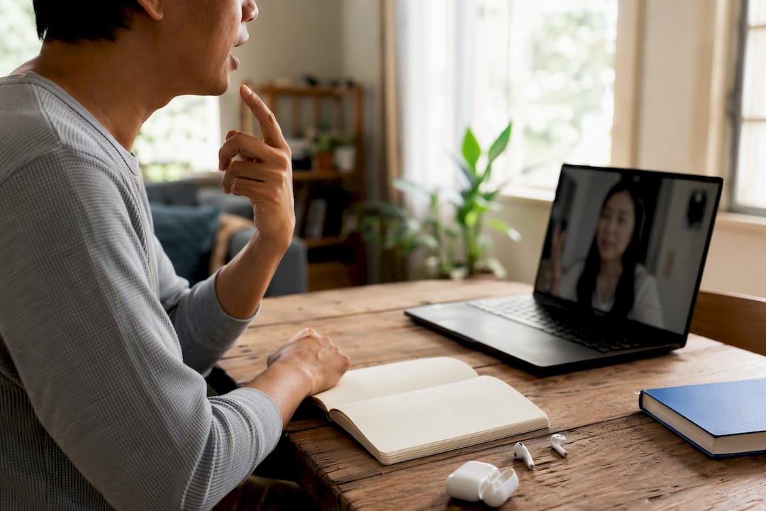 Adult practicing Thai language tones at home desk